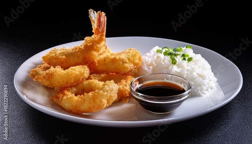 a plate of tempura shrimp rings with rice and soy sauce on a white plate against black background