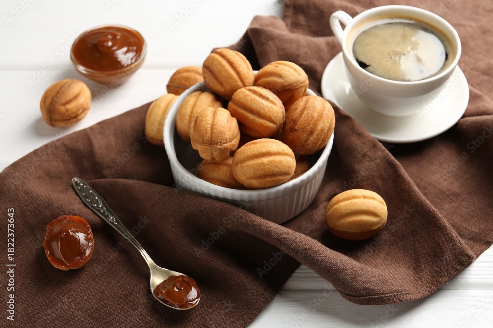 Fototapeta premium Delicious nut shaped cookies with boiled condensed milk served with coffee on white wooden table