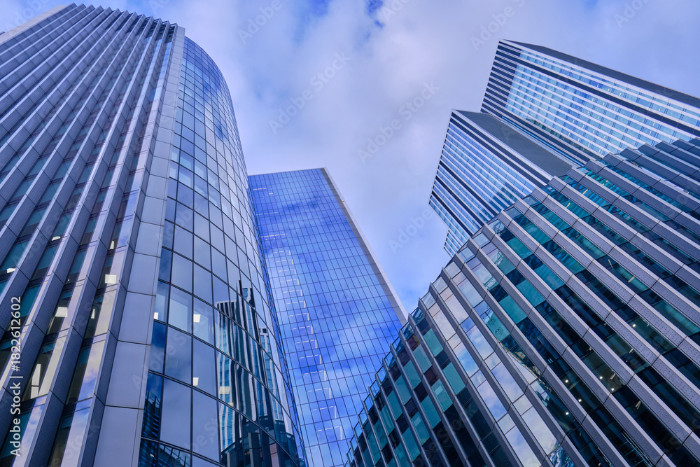 Fototapeta premium Wide-angle view of skyscrapers in the City of London against a blue sky with light cloud.