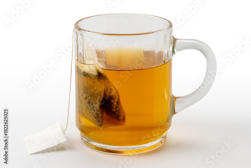 Relaxing digestive herbal tea with chamomile and licorice in a filter bag to be steeped in boiling water in a glass cup isolated on white with clipping path included