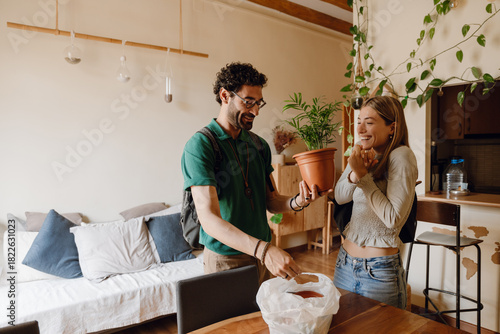 Φωτογραφία A man and a woman stand at a table while laughing and looking at a potted plant