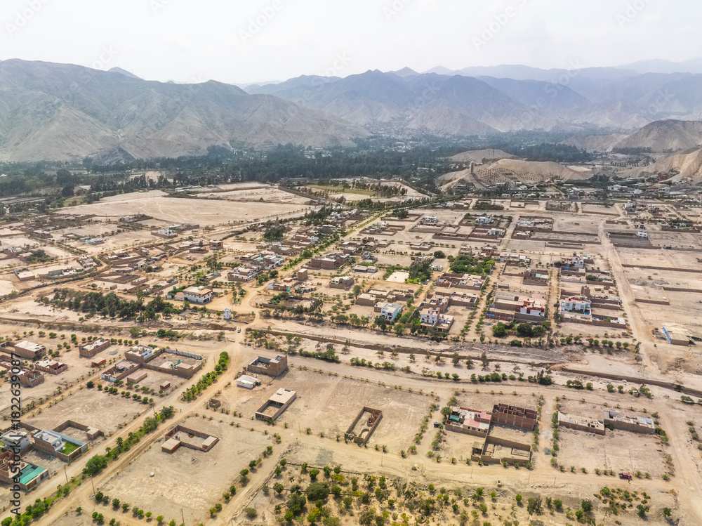 Obraz premium Aerial panoramic view of urban expansion in the Cieneguilla valley near Lima Peru showing residential neighborhoods and green areas surrounded by arid mountains.