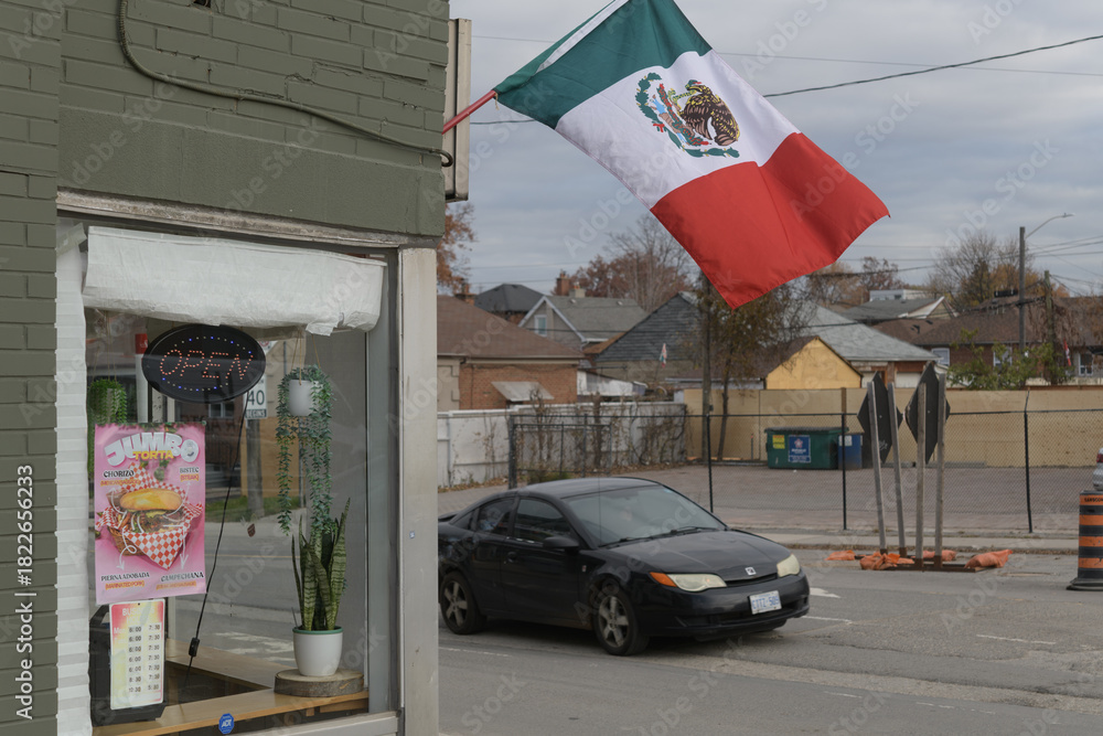 Fototapeta premium exterior of Sofia’s Sweet Cake and Bakery with Mexican flag and vehicle heading SB on Caledonia at Eglinton Av W, Toronto (600 Caledonia Rd)