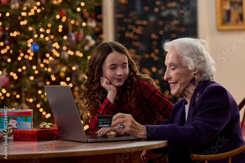 Grandmother and granddaughter shopping online together with credit card during the Christmas holiday season