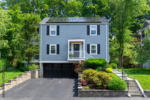 Elegant two-story gray family home with solar panels and lush greenery in Newton, Massachusetts, USA
