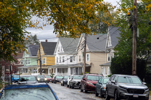 Residential street lined with colorful houses and parked cars on a rainy autumn day in the Brighton area of Boston, Massachusetts, USA
