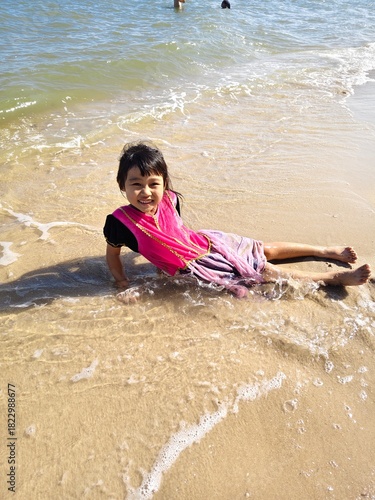 Cute little asian girl playing on the beach 