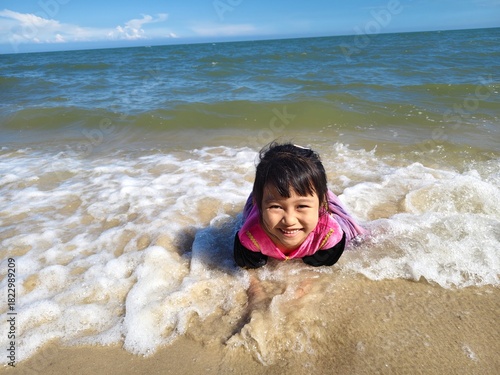 Cute little asian girl playing on the beach 