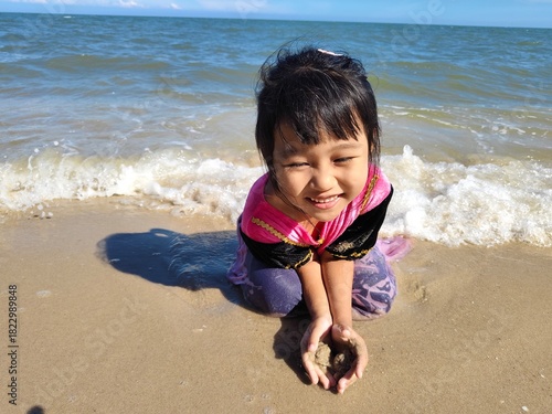 Cute little asian girl playing on the beach 