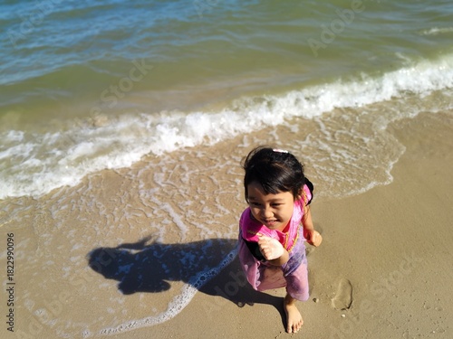 Cute little asian girl playing on the beach 