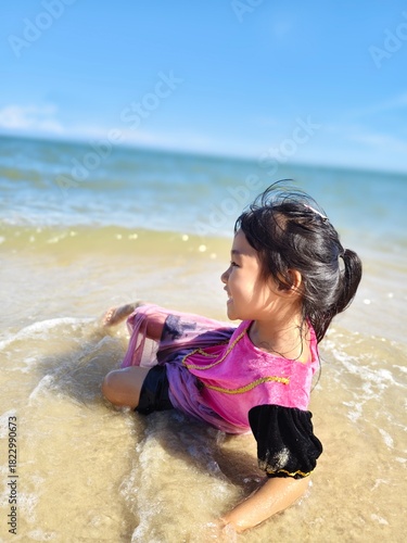 Cute little asian girl playing on the beach 