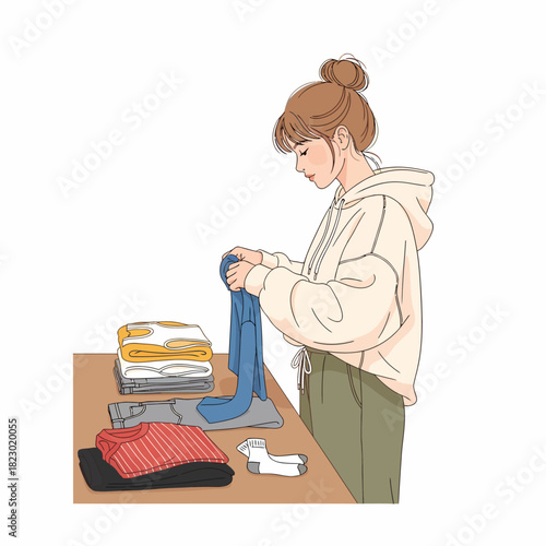 Young woman diligently folding laundry on a wooden table at home.