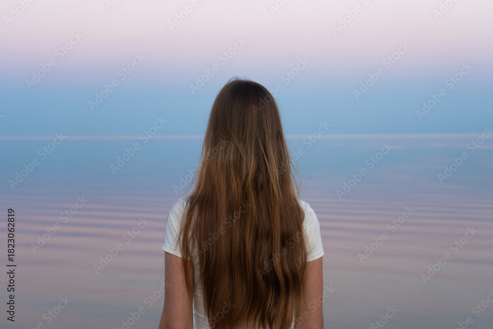 Obraz premium Girl gazes towards the horizon, her flowing hair reflecting a sense of freedom.