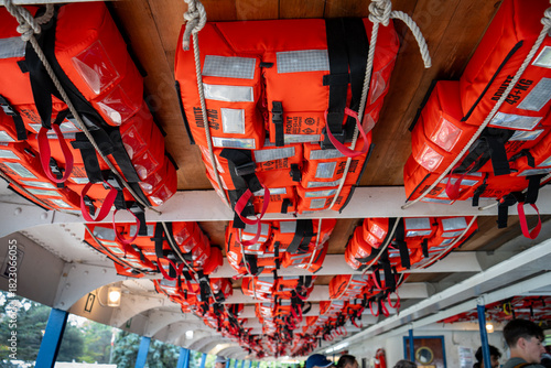 Rows of bright orange life vests hanging overhead, ready for water safety.