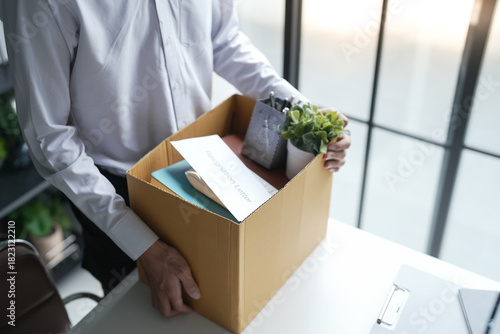 Tableau sur toile Business man sending resignation letter and packing Stuff Resign Depress or carrying business cardboard box Change of job or fired from company resign