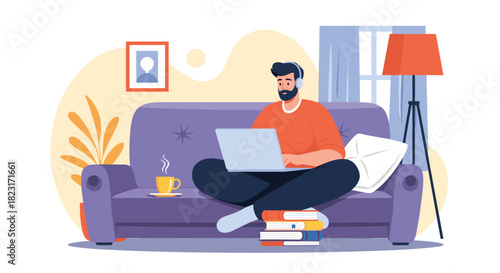 A bearded man works comfortably from home, sitting cross-legged on a sofa with a laptop, enjoying a hot drink and books nearby.