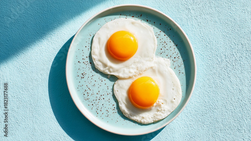 Cuadro en lienzo Two fried eggs on a blue plate are ready to be eaten for a protein breakfast