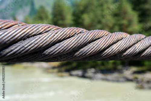 Close-up shot showcasing the weathered texture of a thick, twisted steel cable bridge support