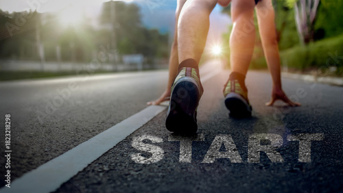 A runner in starting position on an outdoor road with strong sunlight, symbolizing motivation, determination, and the beginning of a new journey. Ideal for concepts of start, goal setting, fitness, an