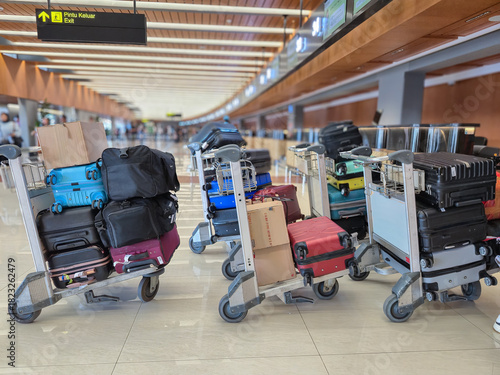 trolleys with piles of suitcases and cardboard boxes are queuing and being weighed before being put into the plane's baggage compartment.