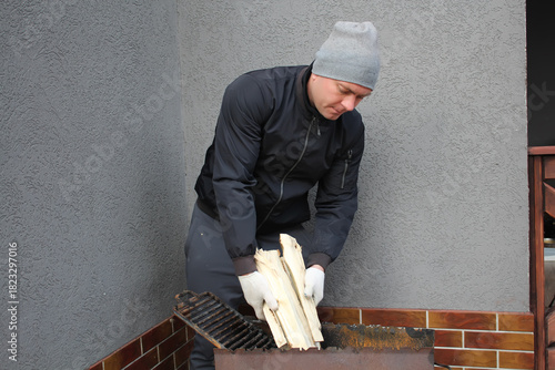 Men's chores, men's daily work tasks. A man stacks firewood in the grill.