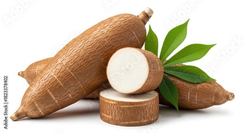 Fresh cassava root, whole, sliced, with green leaves, on white.