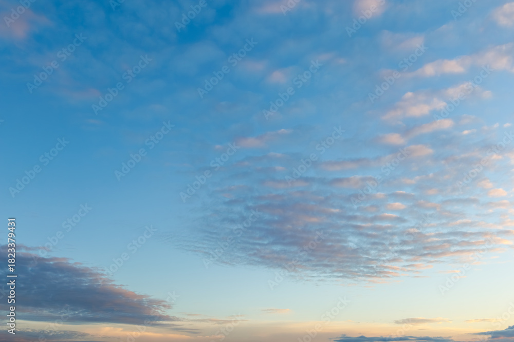 Fototapeta premium A serene sky scene with gentle pastel clouds illuminated by warm evening light, creating a peaceful and open atmosphere perfect for backgrounds.