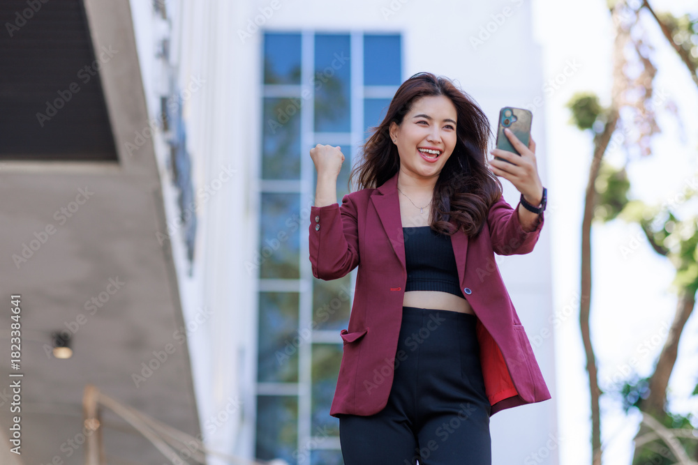Fototapeta premium Excited woman celebrating success looking at phone