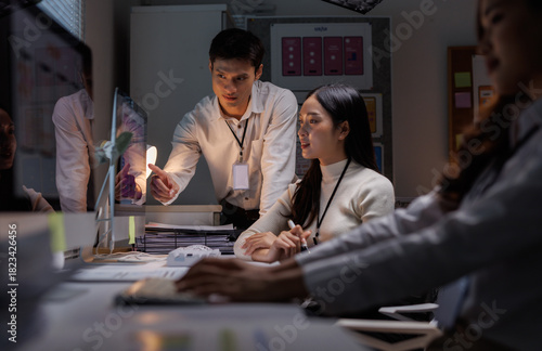 Colleagues collaborating on computer screen during late night work