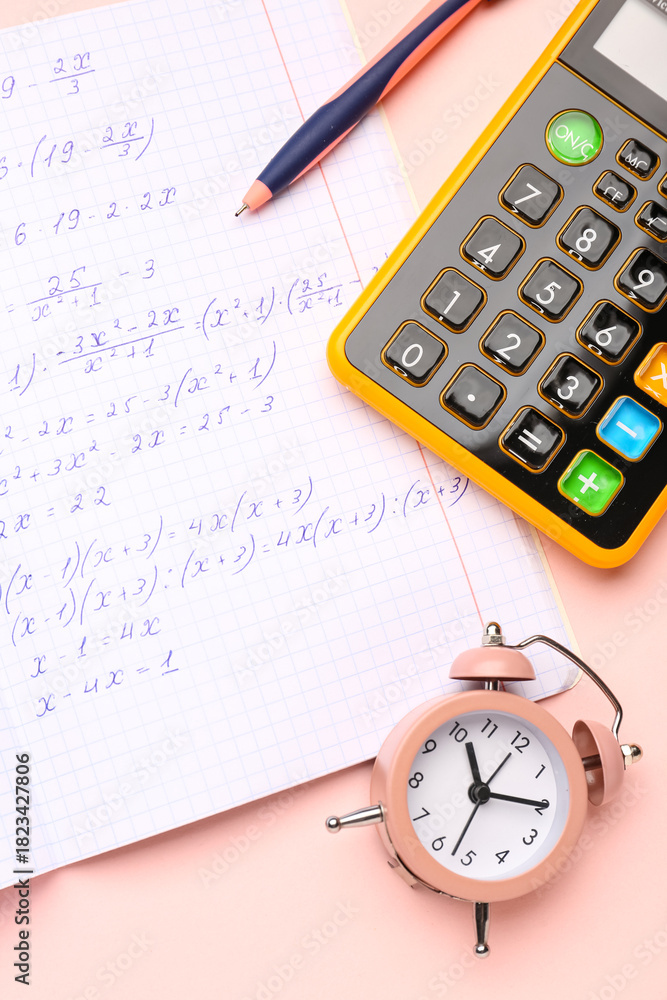 Naklejka premium Copybook with maths formulas, pen, calculator and alarm clock on pink background