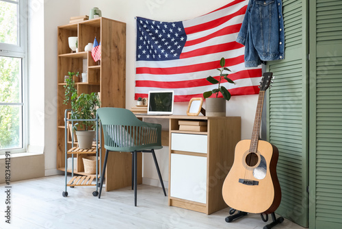 Comfortable workspace with laptop, USA flag and guitar in home office