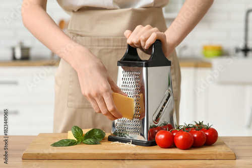 Young woman grating cheese ...