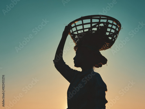 Wallpaper Mural Silhouette of person carrying basket on their head is set against vibrant sunset sky, evoking sense of tradition and resilience Torontodigital.ca
