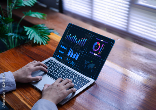 A person works on a laptop with a dashboard for data analysis and database-connected metrics for operations in finance, sales, marketing, digital transformation, and business intelligence.  
