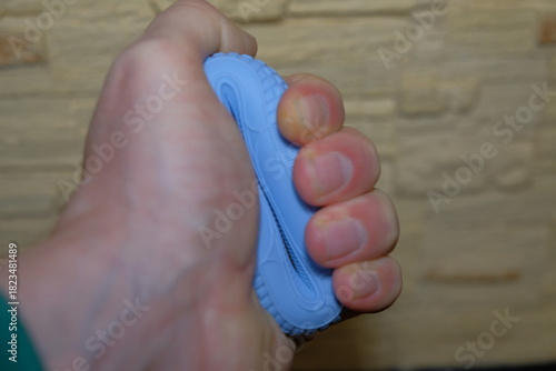 A man squeezes a hand expander with his hand