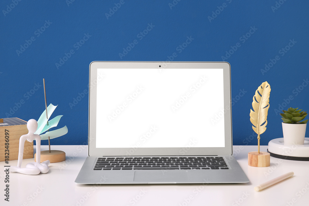 Fototapeta premium Modern laptop, decor and sticky notes on light table near color wall