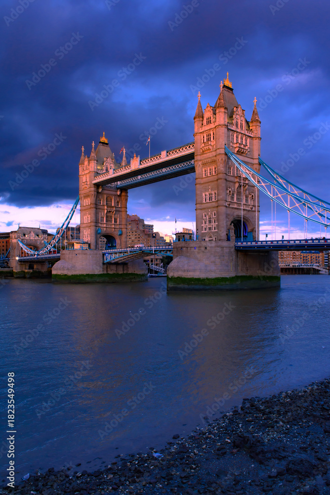 Obraz premium Tower Bridge, the iconic landmark of London spanning the River Thames, captured in a romantic moment. The elegant structure, illuminated against the water, evokes a sense of charm and timeless beauty.