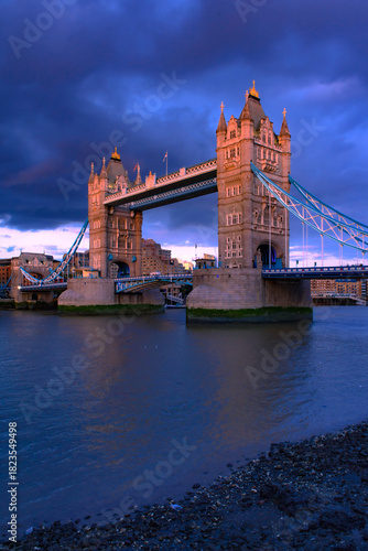 Tower Bridge, the iconic landmark of London spanning the River Thames, captured in a romantic moment. The elegant structure, illuminated against the water, evokes a sense of charm and timeless beauty.