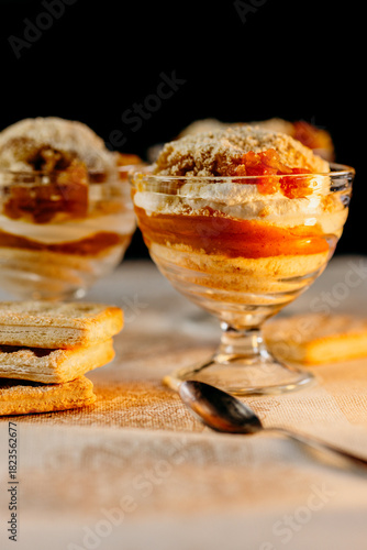 Three pumpkin cheesecake trifles in glass cups with cookie crumbs, warm homemade dessert scene.