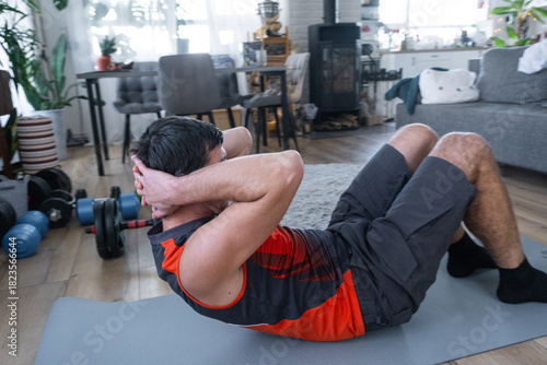 A man does abs exercises at home on a fitness carpet