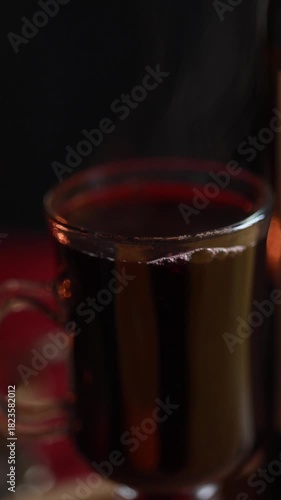 Warm mulled wine being poured into a clear glass, cozy winter mood, steam rising, inviting seasonal atmosphere.