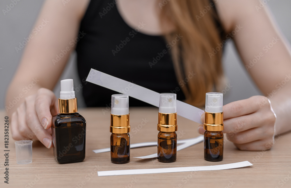 Fototapeta premium Women's perfumes in dark bottles with atomizers, blotter for testing, searching for your scent