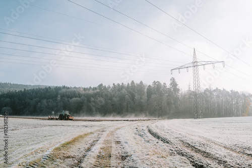 Ein Traktor pflügt einen dampfenden Acker an einem kalten Wintermorgen mit Sonnenschein
