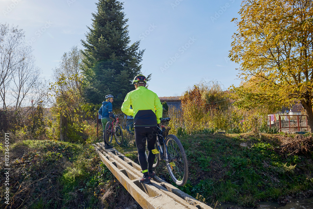 Fototapeta premium An old man who is passionate about cycling rides his bike with his son, enjoying a beautiful autumn day.