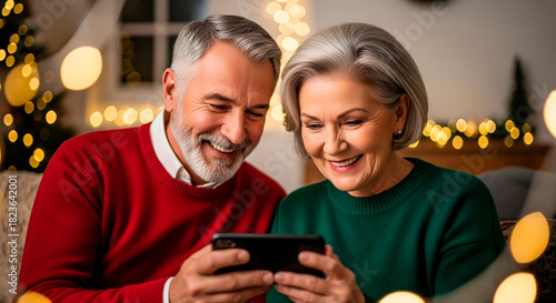 Elderly man and woman looking at digital tablet during Christmas. Merry Christmas and Happy New Year holiday. Senior couple video calling on smartphone.