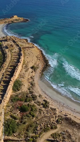 Aerial drone view of the coastal ruins of Leptis Magna, an ancient Roman city in Libya. Vertical