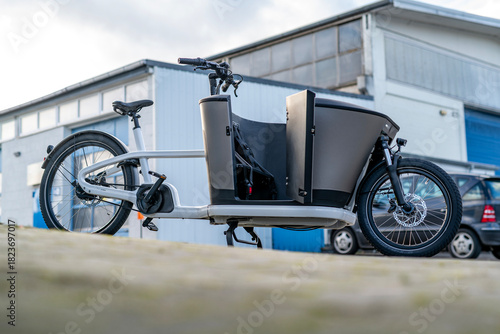 Electric Cargo Bike in Front of Industrial Building, Backlit Outdoor Urban Scene