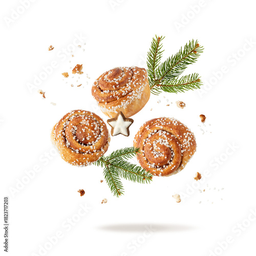 Fresh baked cinnamon buns, Christmas tree branch and gingerbread star cookies flying falling isolated on white background. Traditional swedish sweet pastry kanelbulle.