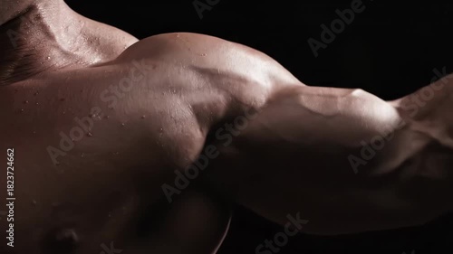 Muscular mans sweaty bicep and deltoid flex during intense workout. Concept of bodybuilding, sport, fitness.