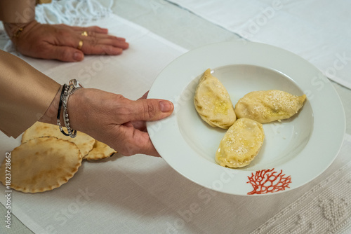 A person holding a porcelain plate containing homemade pasta called culurgiones